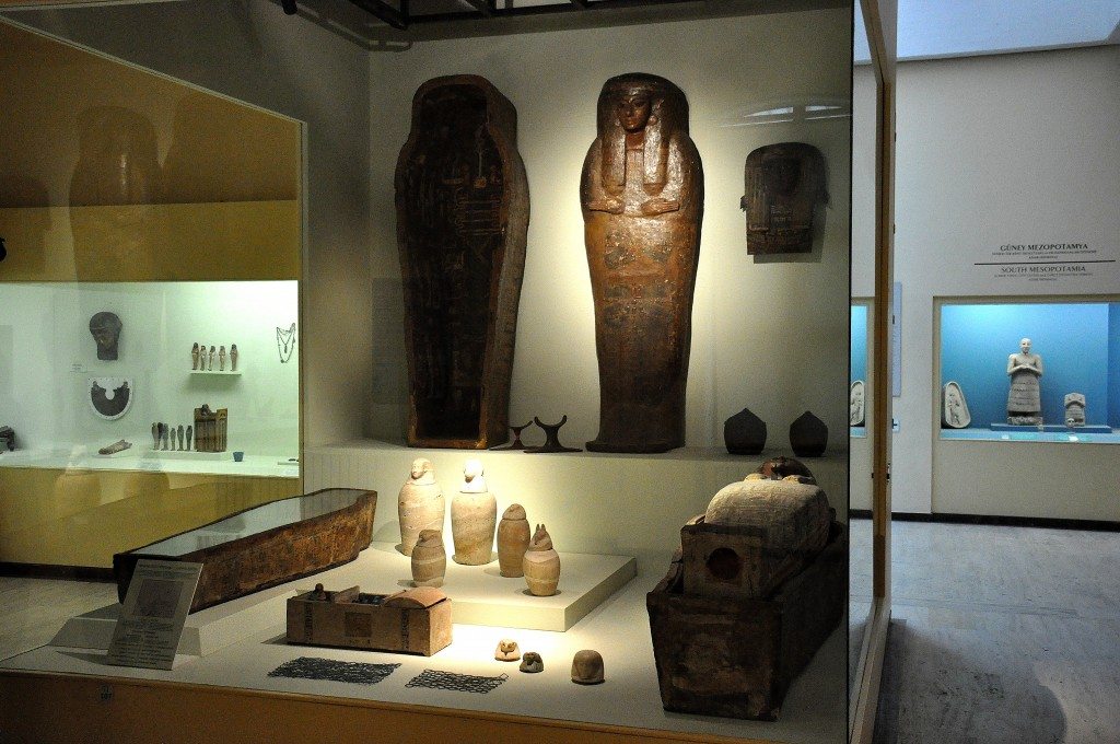 Grave finds from ancient Egypt. In this grave, we can see coffins, mummies, canopic jars, head part of a wooden coffin, baskets for beads, wooden chest for ushabties, and beadwork covers. 