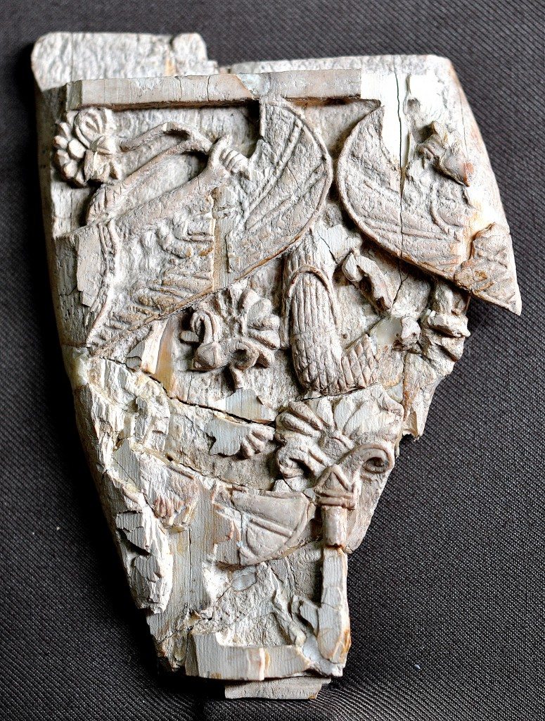 A fragment of a carved ivory plaque. On the left, the arm of a person holds a branch of lotus. Part of his wing appears. On the right, part of a wing of another person can be seen. Neo-Assyrian period, 9th-7th centuries BCE. From Nimrud, Mesopotamia, Iraq. (The Sulaimaniya Museum, Iraq). 