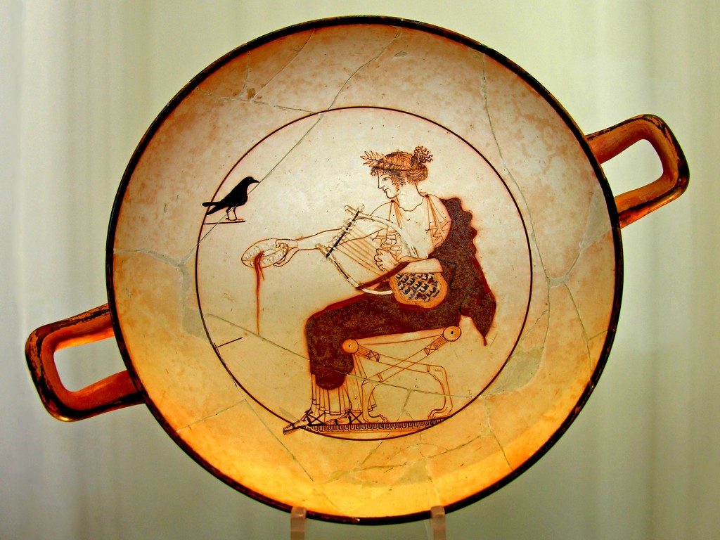 A kylix depicting the god Apollo pouring a libation and holding an early version of the lyre (chelys) which was made from the shell of a tortoise. The bird may represent the crow which announced the marriage of the nymph Aigle-Korone, the daughter of King Phlegyas. Provenance: Delphi, 480-470 BCE, artist unknown. (Delphi Archaeological Museum).