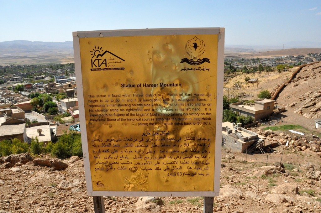 This sign mentions "Kurdistan Tourism Association and The Governorate of Hawler." It describes the relief in 3 different languages. The sign lies at the foot of the mountain. Note the village on the background. ©Osama S. M. Amin. 
