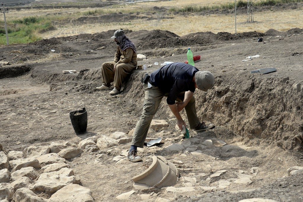 One of the French archaeological team excavates pottery fragments; part of a large pottery pot can be seen. Photo © Osama S. M. Amin. 