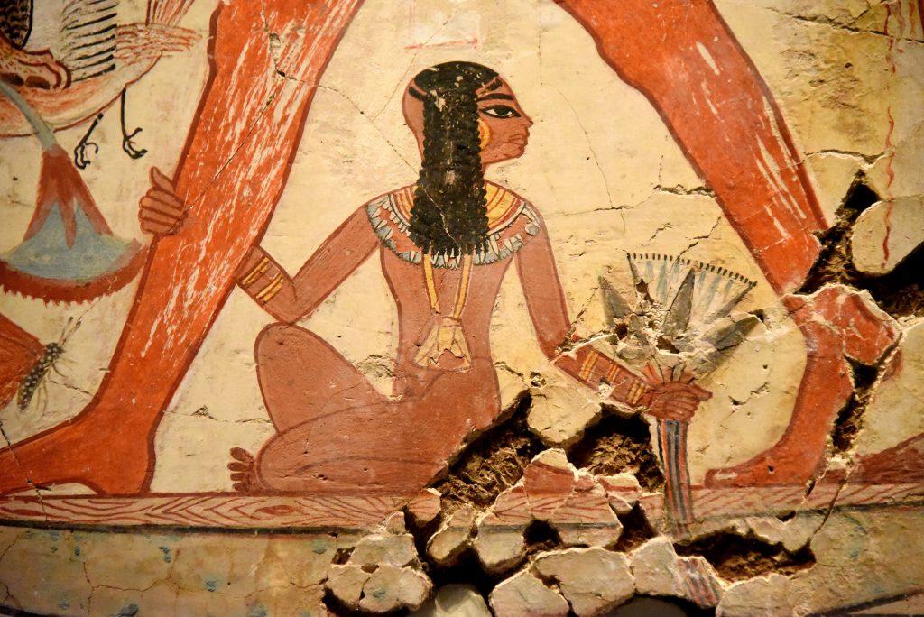 Nebamun's daughter sits on the boat below the figure of her father. She grips her father's right leg with her right hand while her left hand grips a lotus flower. Photo © Osama S. M. Amin.