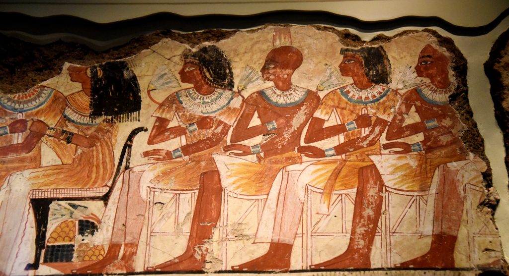 The young men sit on rows of stools, beside a group of young women who sit on chairs with cushions. Men and women skin are painted in different colors; the men are tanned while the women are paler. In one place, the artists altered the drawing of these wooden stools and corrected their first skete with white paint. The Brtiish Museum, London. Photo © Osama S. M. Amin. Nebamun tomb-chapel.