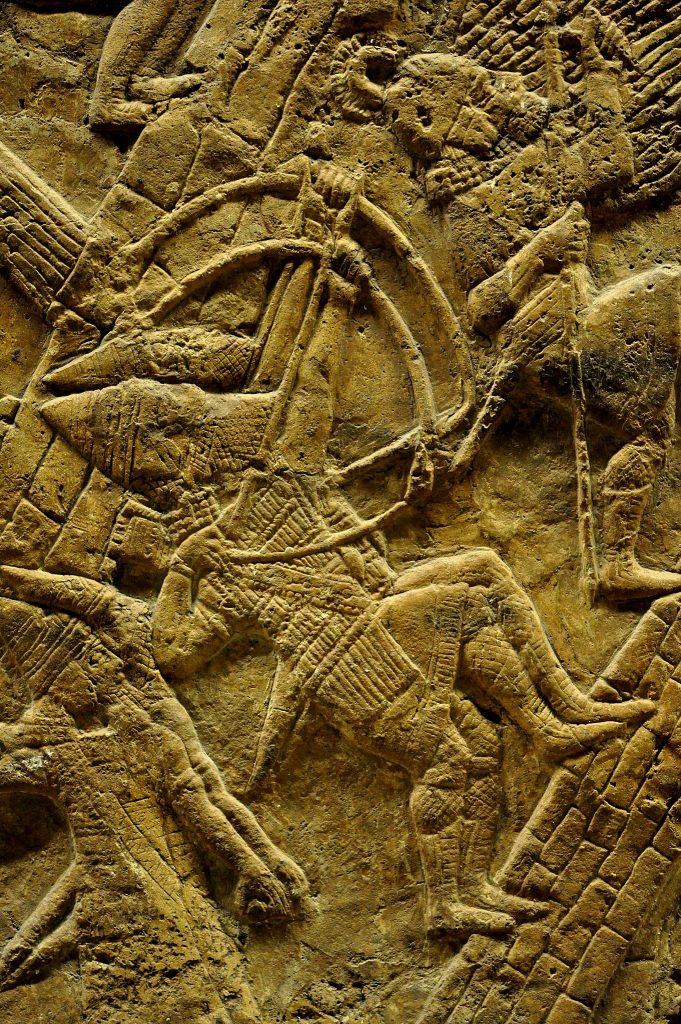 Assyrian slingers and archers are ascending up, on the artificial ramp, to the city walls. They are being led and protected by a spearman who holds a large rounded shield. 