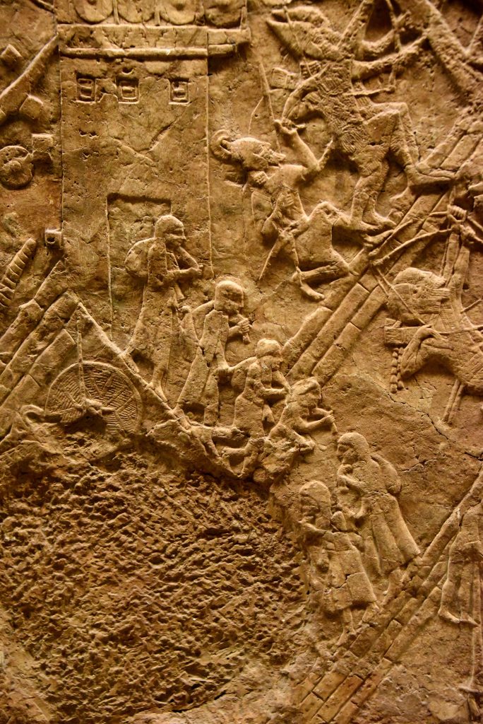 The Lachish defense forces had started to collapse. The city gate has been opened and the city's people are fleeing Lachish, holding belongings, whatever they could bring with them. This detail shows women and one man; they are walking down the hill and have reached the Assyrian artificial ramp. It seems that the Assyrian army let them go, without killing them on the spot. The surrounding battle field is like hell; the Assyrian continue to progress successffully while the defenders of Lachish are desperately resisting the overwhelming invasion. From Nineveh (modern-day Mosul Governorate, Iraq), Room XXXVI of the South-West Palace, panels 7. The British Museum, London. Photo © Osama S. M. Amin. 