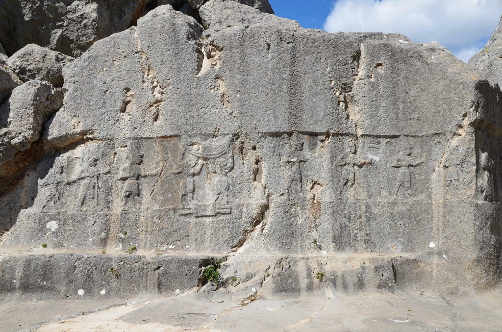 Chamber A, two bull men stand between male Hittite gods on the hieroglyphic symbol of the earth and supporting the sky.