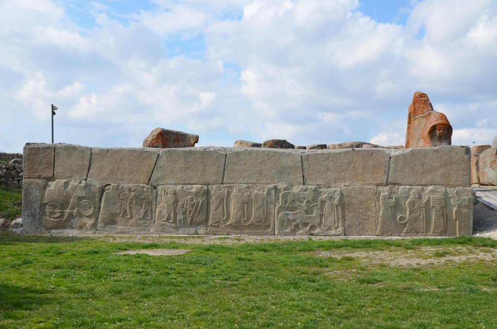 The external facade of the western tower located in front of the Sphinx Gate ornamented with relief-decorated orthostates depicting a religious ceremony in honour of the Storm God. Hittite
