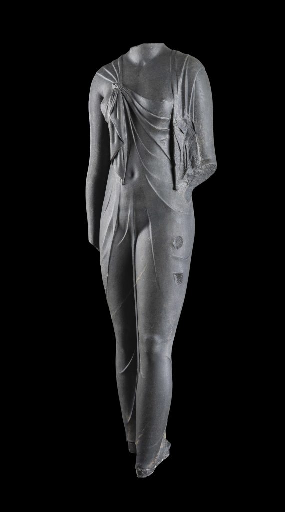 Cut in hard, dark stone, this feminine body has a startlingly sculptural quality. Complete, it must have been slightly larger than life-size. The statue is certainly one of the queens of the Ptolemaic dynasty (likely Arsinoe II) dressed as the goddess Isis, as confirmed by the knot that joins the ends of the shawl the woman wears, which was representative of the queens during this time period. The statue was found at the site of Canopus. ©Franck Goddio / Hilti Foundation - Photo: Christoph Gerigk. Sunken Cities exhibition.